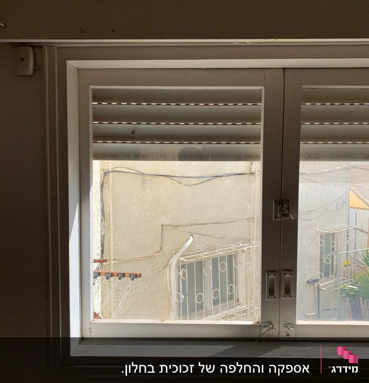 חלון זכוכית עם תריסים פתוחים חלקית